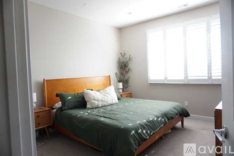 A bedroom with a bed, nightstand, and window.