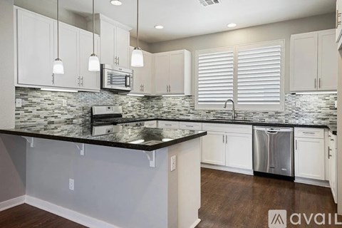 A kitchen with white cabinets and a black counter top.