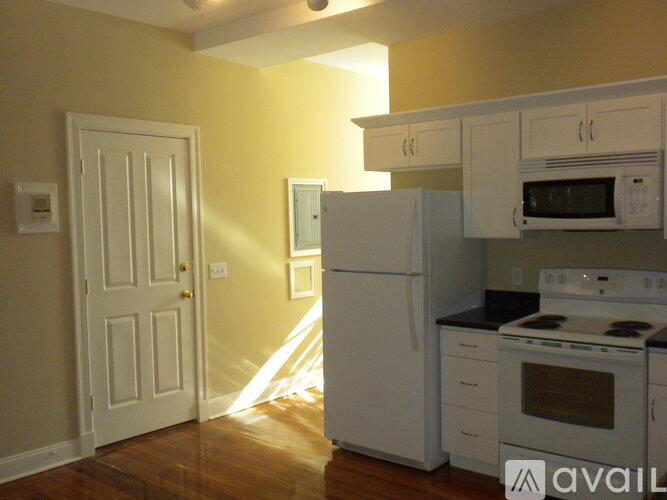 A kitchen with white appliances and wooden floors.
