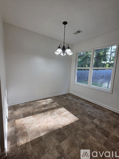 A room with a tiled floor and a window showing trees outside.