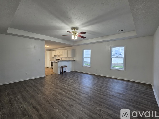 A spacious room with wood flooring and a ceiling fan.