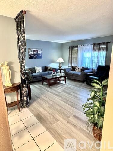 A living room with a grey couch and a wooden floor.