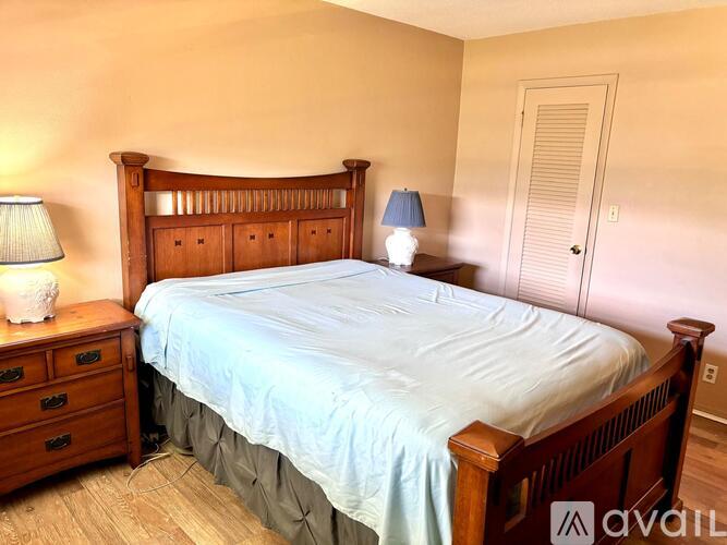 A bedroom with a bed, nightstand, and lamp.