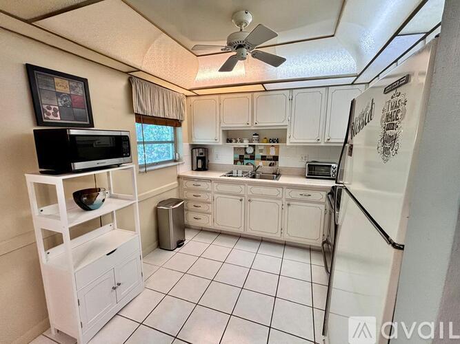 A white kitchen with a fridge on the right.
