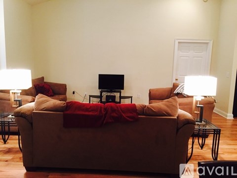 A living room with a brown couch and a TV on a stand.