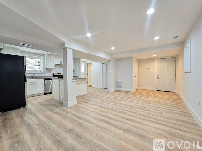 A spacious kitchen with a black fridge and wooden flooring.