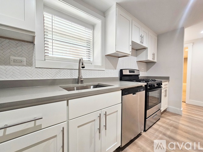 A modern kitchen with white cabinets and stainless steel appliances.