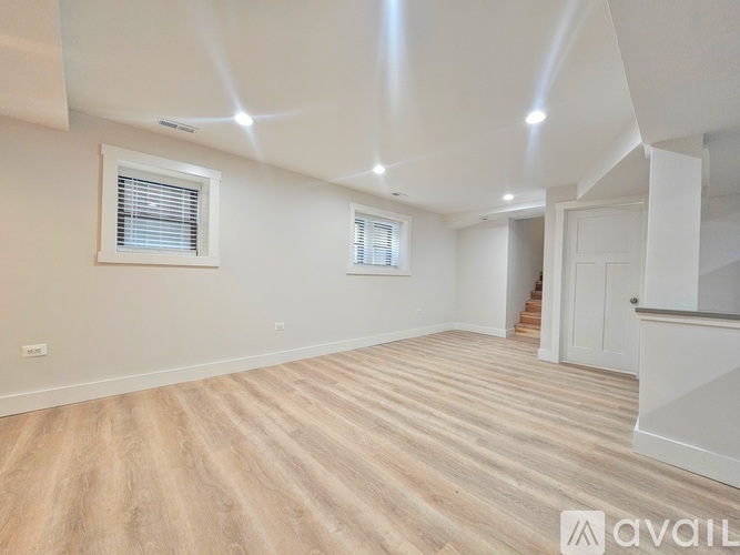 A spacious room with wooden flooring and white walls.