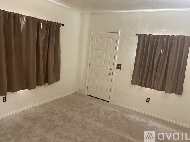 A room with a white door and brown curtains.