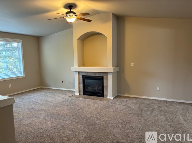 A living room with a fireplace and a ceiling fan.