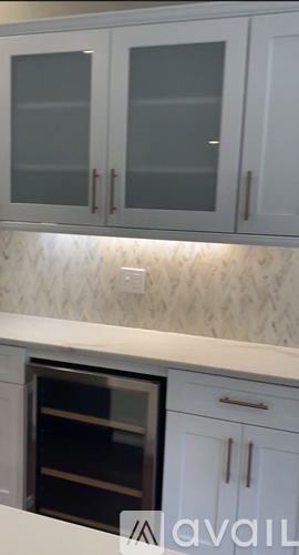 A kitchen with white cabinets and a patterned backsplash.