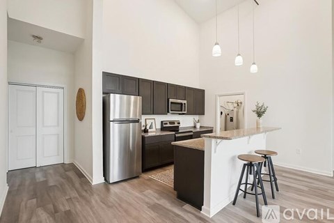 A kitchen with a refrigerator, microwave, and bar stools.