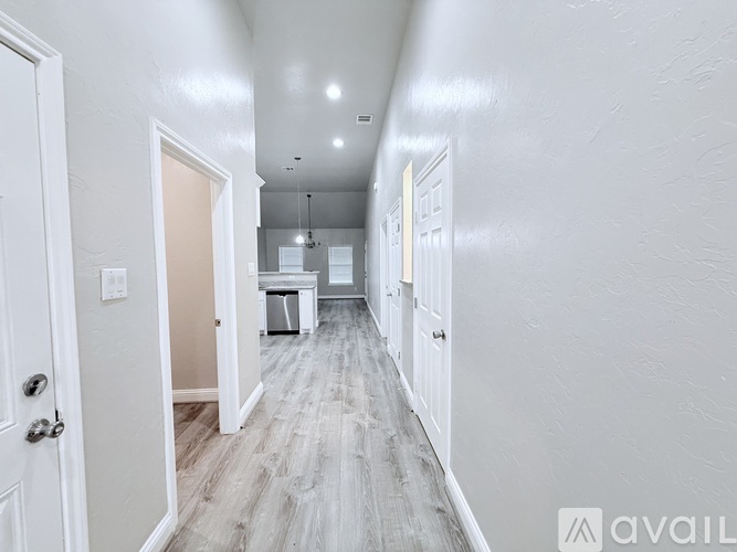 A long hallway with white walls and wood flooring.