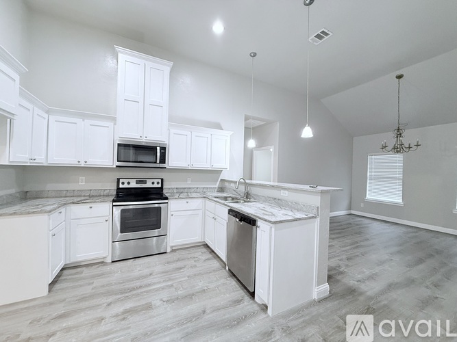 A kitchen with white cabinets and a marble countertop.