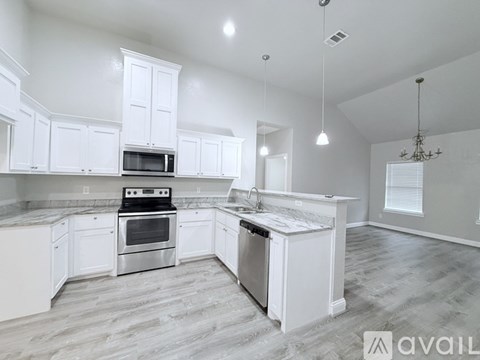 A kitchen with white cabinets and a marble countertop.