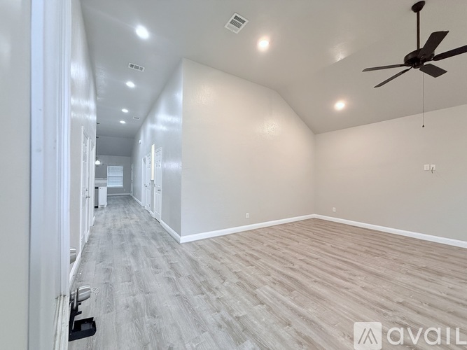 A spacious room with a fan and light grey flooring.