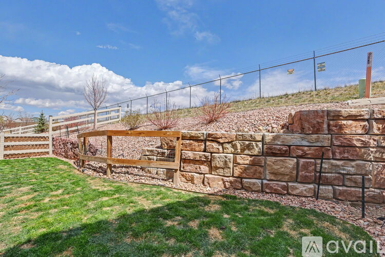 A fenced grassy area with a stone wall and a wooden gate.