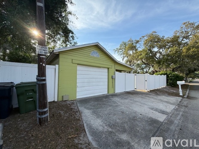 A green garage door is on a house with a white fence.