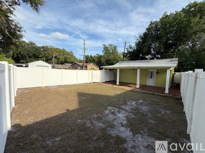A backyard with a white fence and a small building.