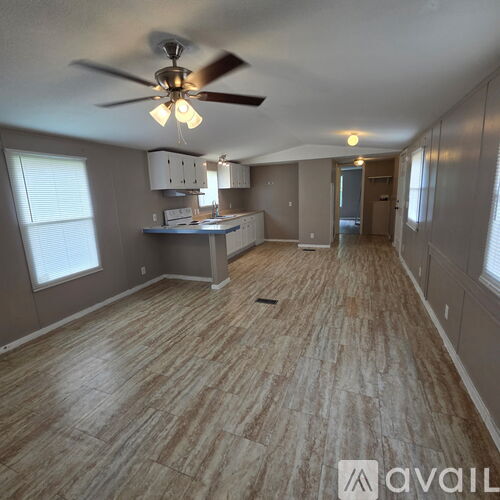 A room with a ceiling fan and wooden flooring.