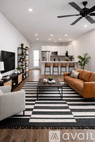 A living room with a striped rug, a grey sofa, a coffee table, a TV, and a bar area.