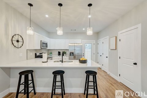 A kitchen with white cabinets and black stools.