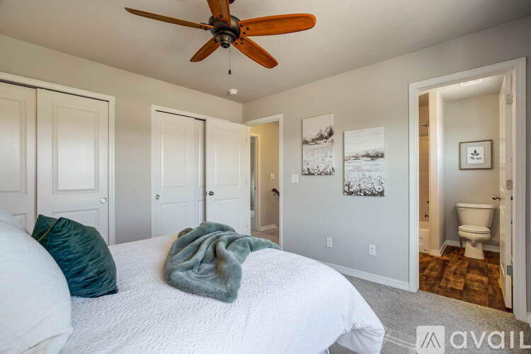 A bedroom with a white bed and a ceiling fan.