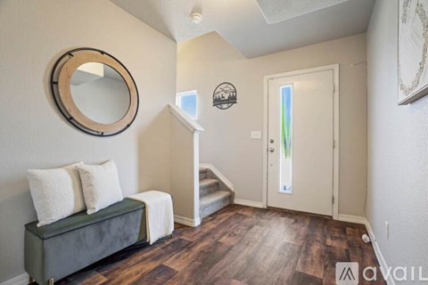 A living room with a green couch and a round mirror on the wall.