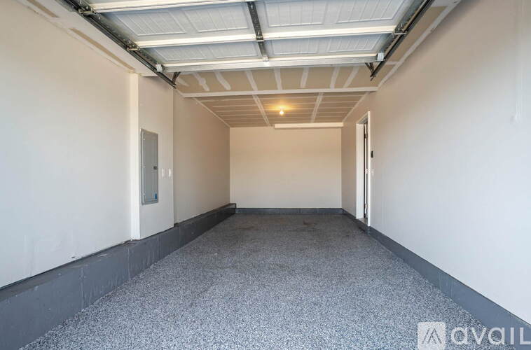 A spacious room with a grey carpet and white walls.