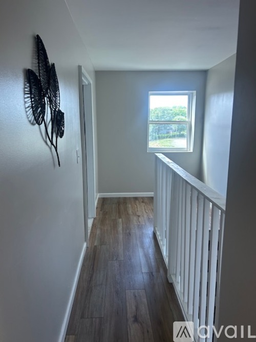 A long hallway with a fan on the wall and a window.