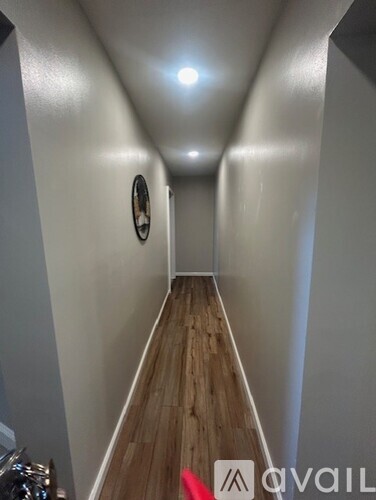 A long hallway with wood floors and white walls.