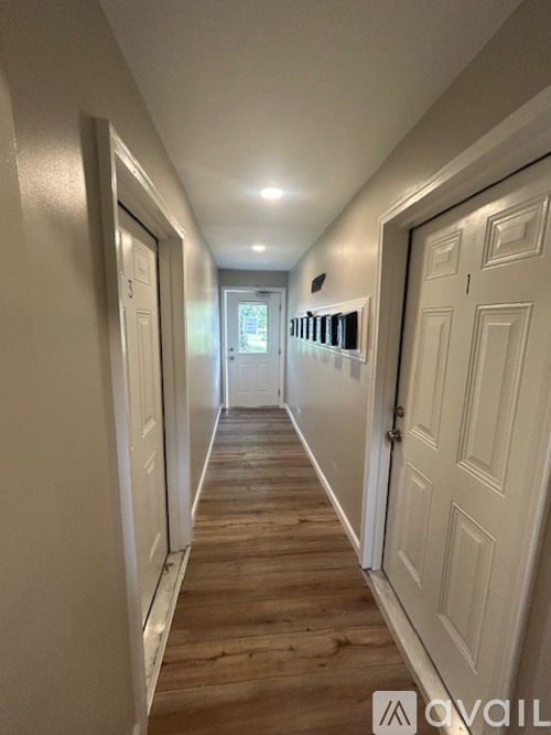 A long hallway with white doors on both sides and a light on the ceiling.