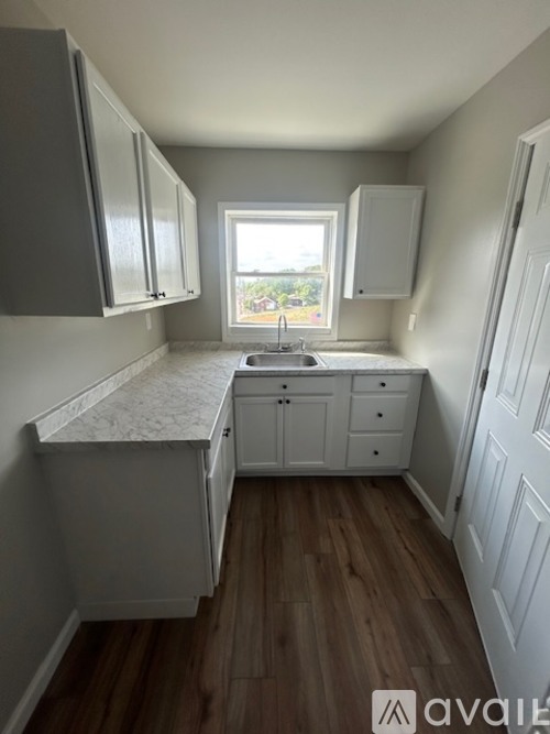 A kitchen with white cabinets and a window.