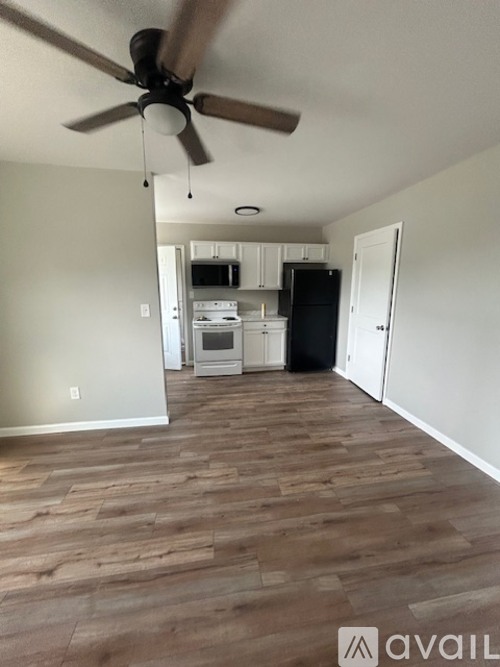 A room with a ceiling fan and wooden flooring.