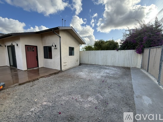 A small house with a red door and a white fence.