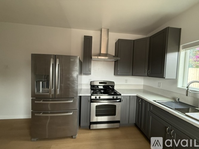 A kitchen with a stainless steel refrigerator, oven, and range hood.