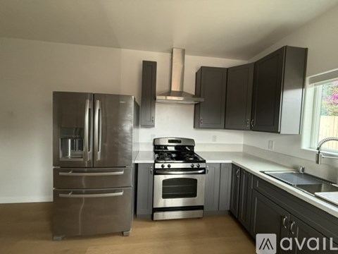 A kitchen with a stainless steel refrigerator, oven, and range hood.