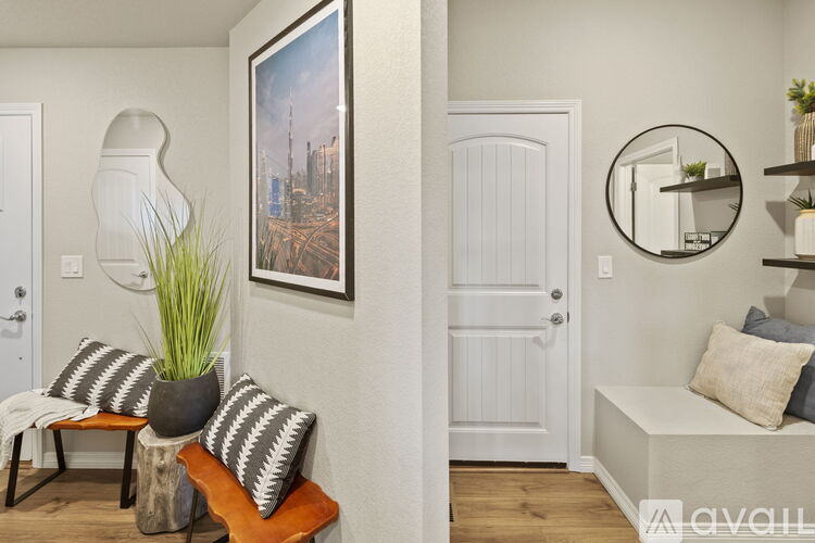 A living room with a white door, a sofa with striped pillows, a potted plant, and a framed picture on the wall.