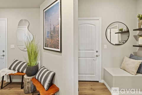 A living room with a white door, a sofa with striped pillows, a potted plant, and a framed picture on the wall.