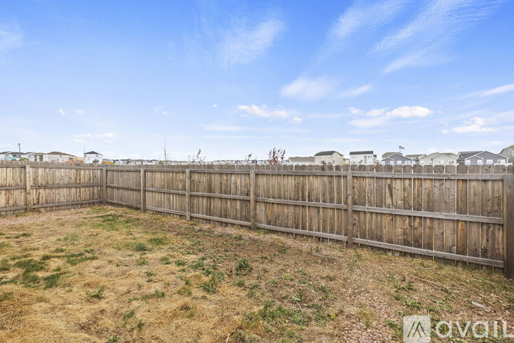 A backyard with a wooden fence and a grassy area.