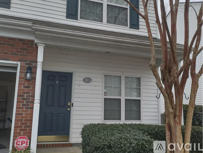 A house with a blue door and a tree in front.