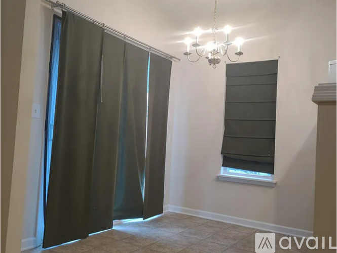 A room with a chandelier, a window with blinds, and a sliding door.