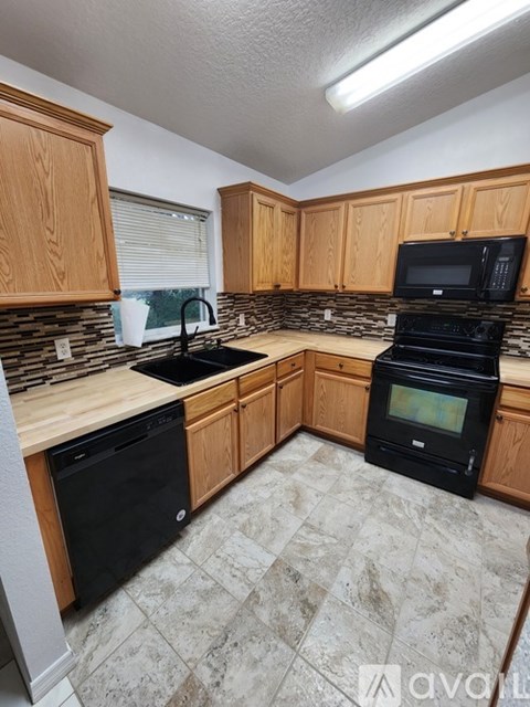 A kitchen with wooden cabinets and black appliances.