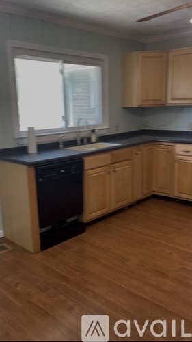 A kitchen with wooden cabinets and a black dishwasher.