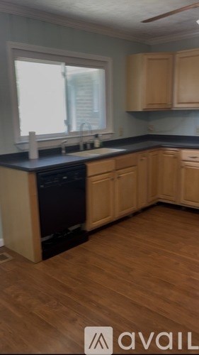 A kitchen with wooden cabinets and a black dishwasher.