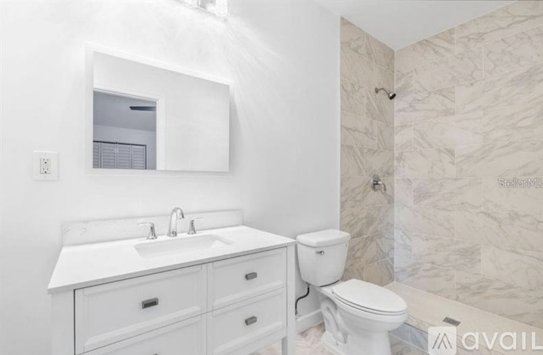 A white bathroom with a sink, toilet and mirror.