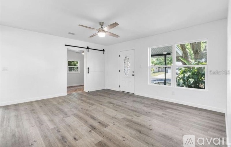 A room with a ceiling fan and sliding glass doors.