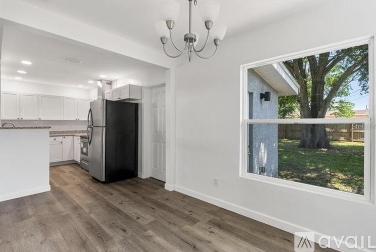 A kitchen with white cabinets and a black refrigerator.