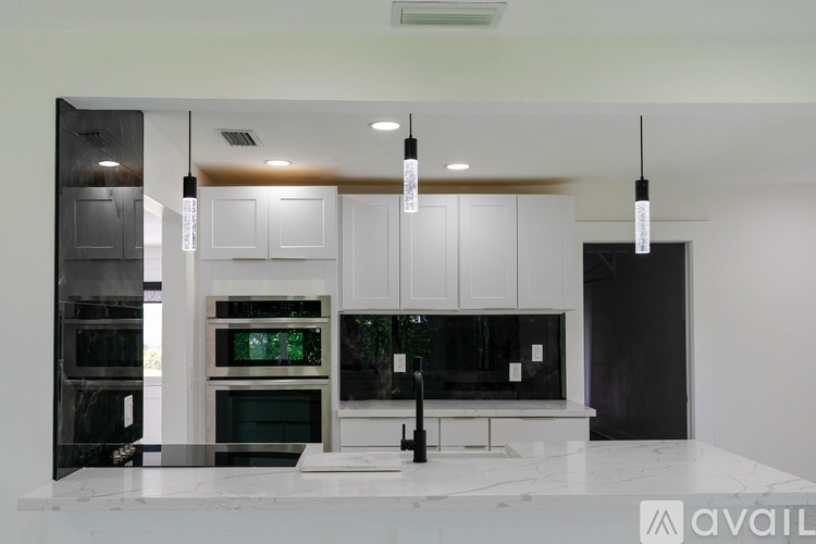 A modern kitchen with black and white cabinetry and a marble countertop.
