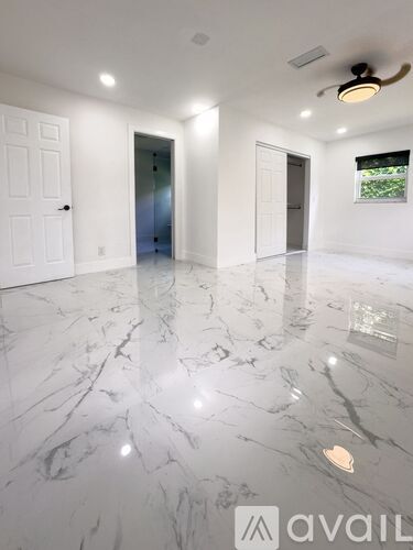 A spacious room with marble flooring and a ceiling fan.